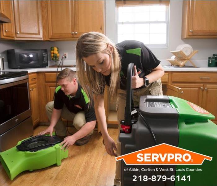 SERVPRO technicians set up drying equipment in a kitchen damaged by water.