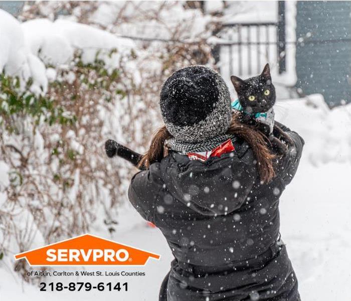 A person carries a wayward pet cat back home during a winter storm.